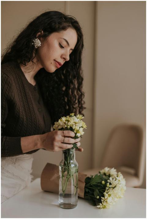 A woman carefully arranges a bouquet of daisies in