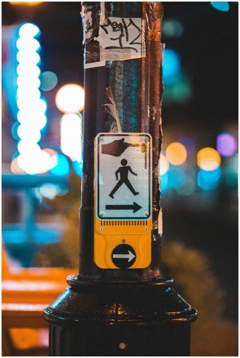 Crosswalk sign on a pole illuminated by streetligh