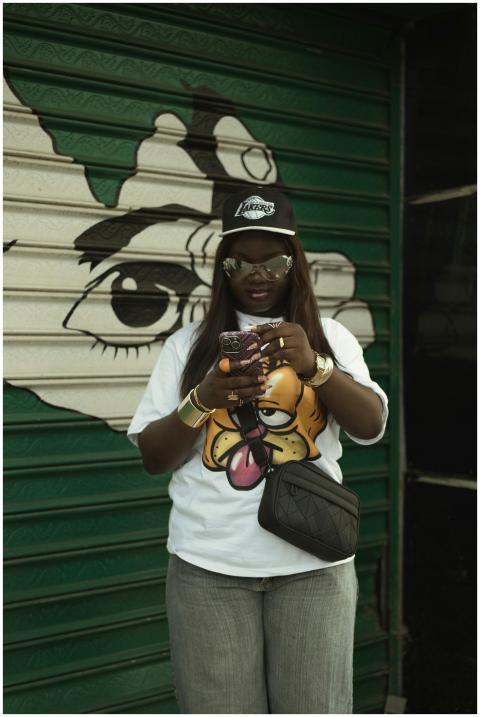 Person in casual outfit, using phone, against vibr