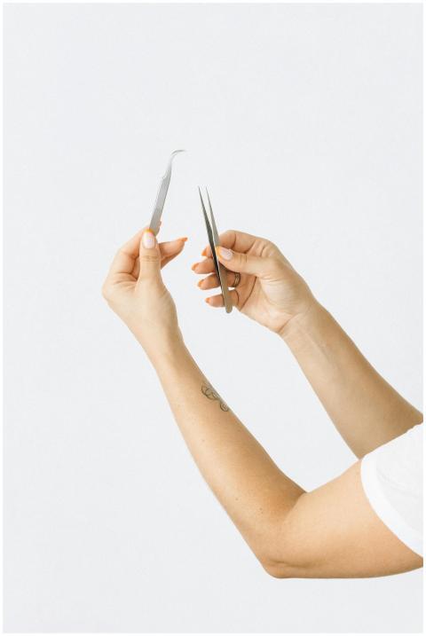 Close-up of female hands holding tweezers and scis