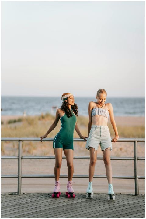 Two women enjoy roller skating by the beach at sun