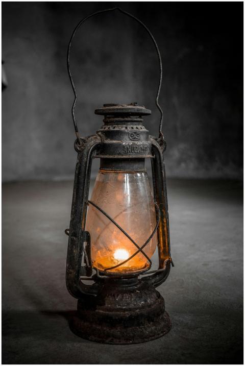An antique lantern illuminated by a candle in a di