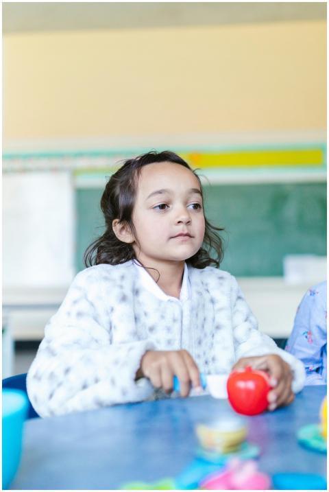 A child in a classroom setting with toys and color