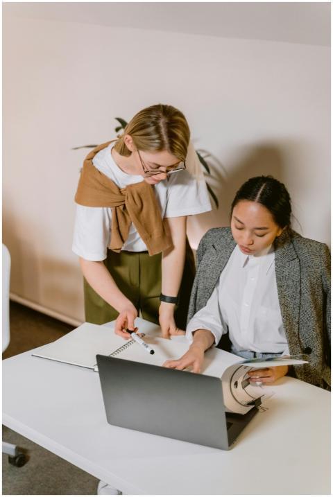 Two diverse colleagues brainstorm over a laptop in