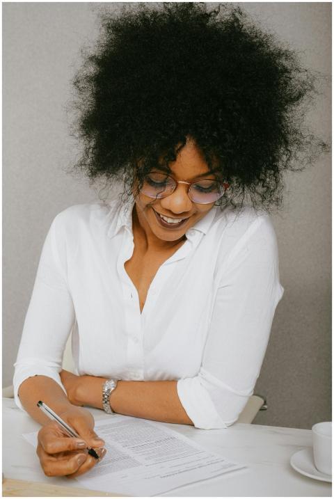 Smiling woman in business attire signing documents