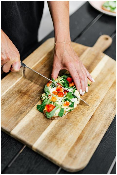 A person cuts a healthy avocado toast topped with