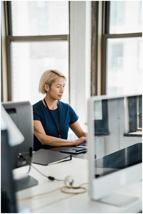 A focused woman working on a computer in a bright,