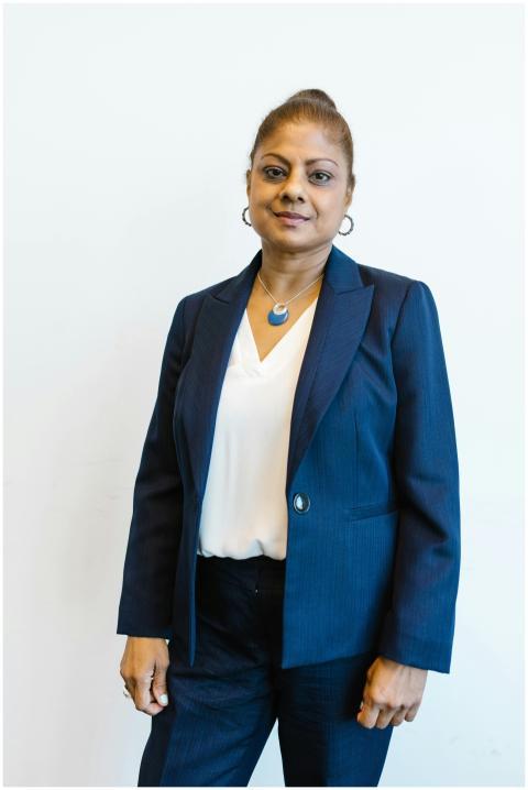 Confident woman in business attire smiling against