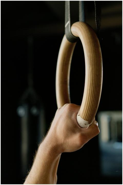 A focused shot of a hand gripping a gymnastic ring