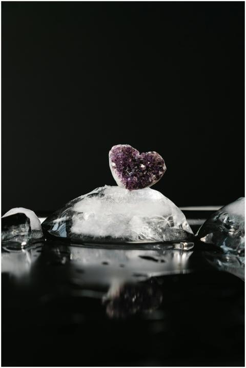 A heart-shaped amethyst crystal atop melting ice a