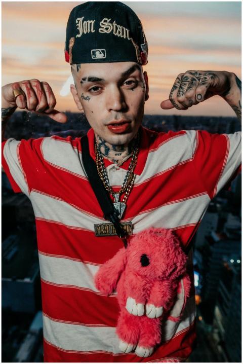 Young man in red striped shirt with tattoos poses
