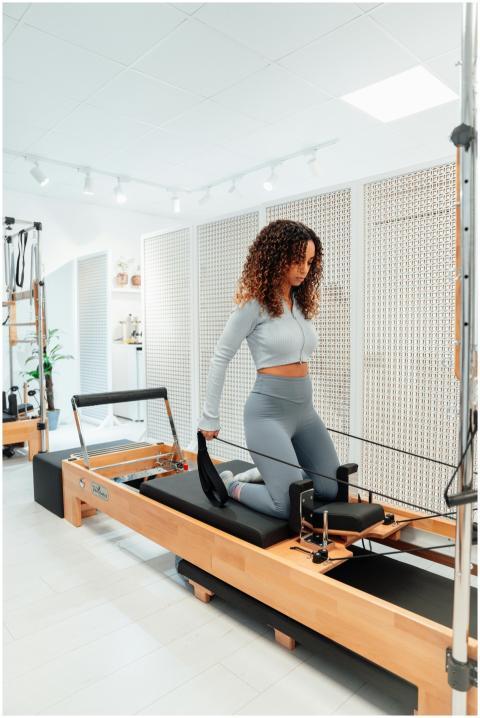 Woman in gray tracksuit exercises on Pilates tower