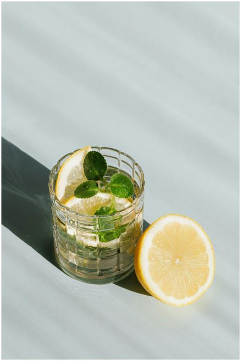Icy lemon mint drink in glass, half lemon beside,