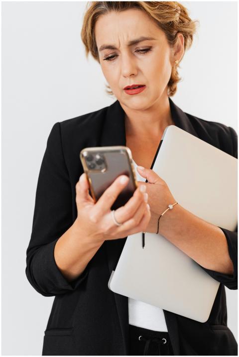 Confident businesswoman multitasking with smartpho