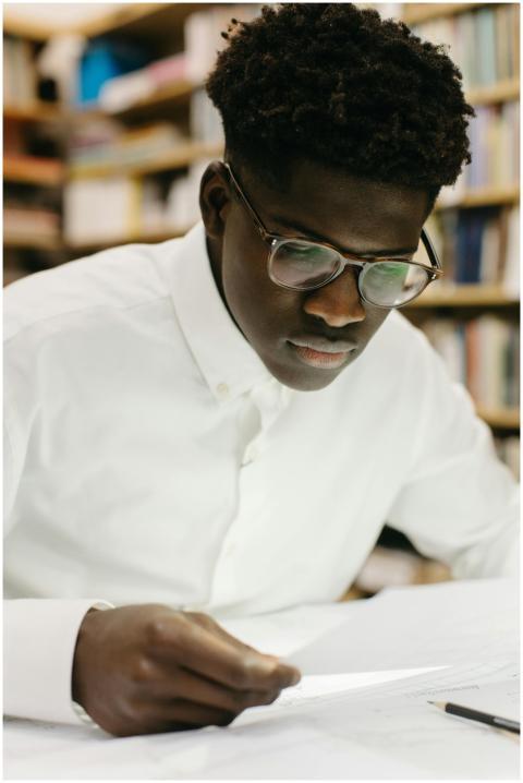 Young man in glasses reading and studying, surroun