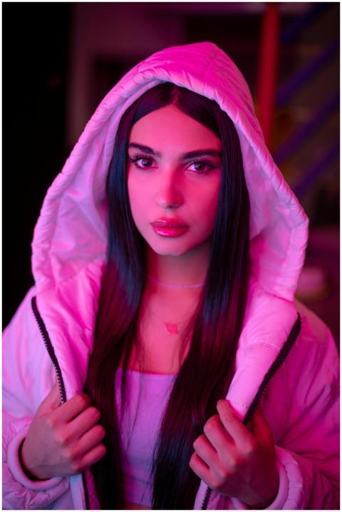A striking portrait of a woman in a neon pink hood