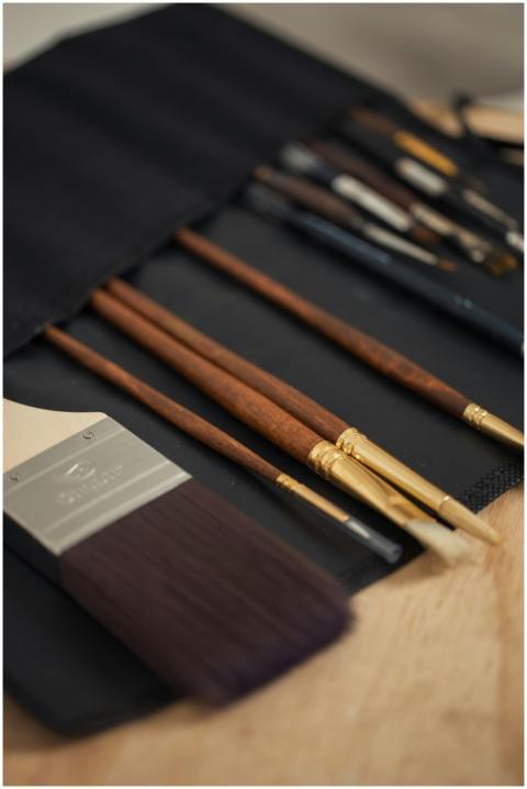 Close-up of various paintbrushes in a fabric holde