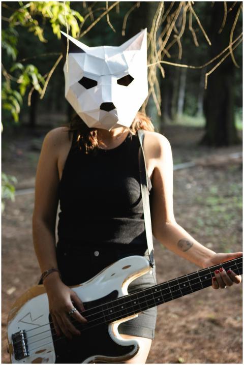 An adult wearing a geometric animal mask plays a b