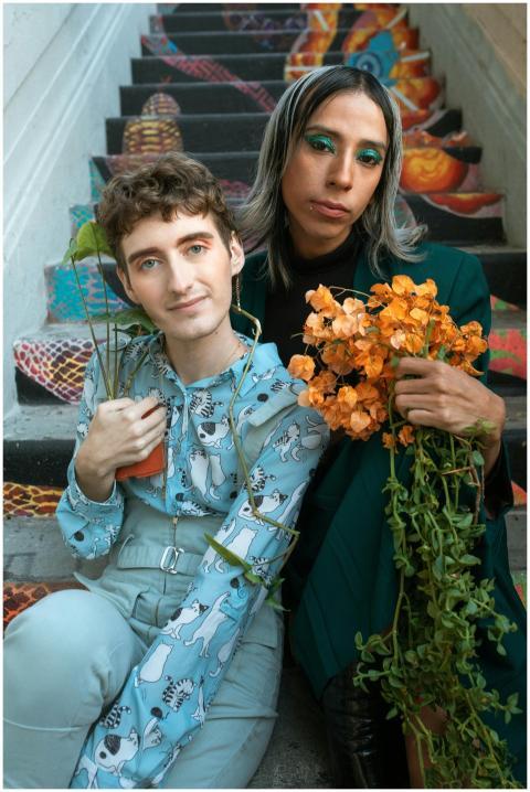 Two individuals pose on colorful stairs with vibra