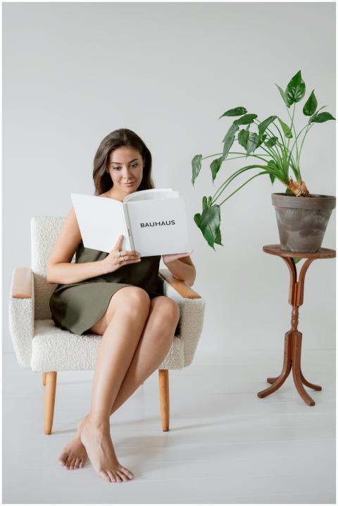 Young woman reading in a cozy chair next to a plan