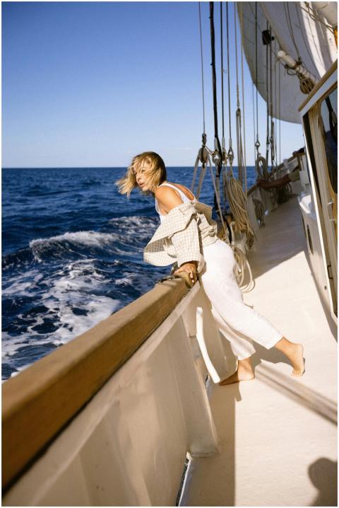 A woman leans over the rail of a sailing ship, enj