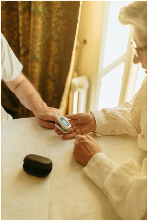 Elderly person using a pulse oximeter indoors for