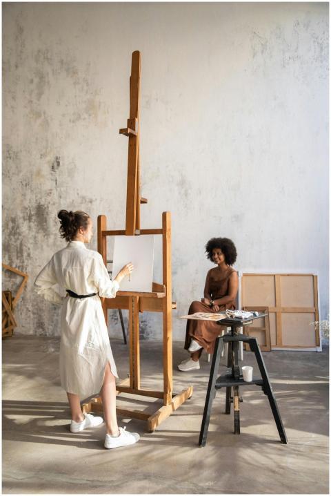 Two women in an art studio with a canvas, easel an