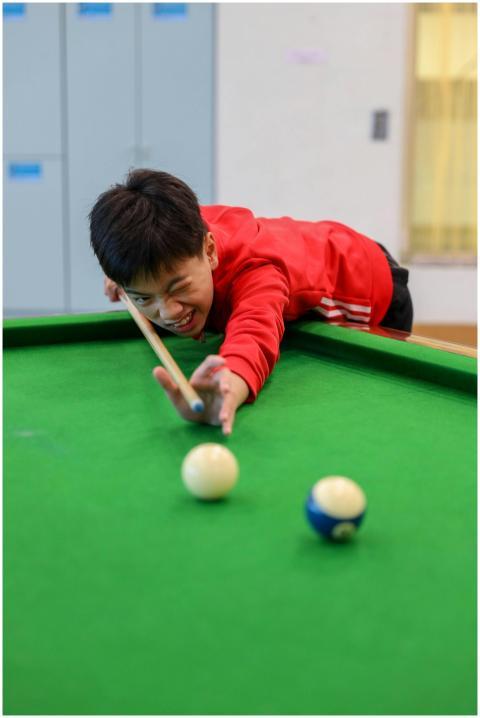 Teen boy focusing on shot in billiard game, indoor