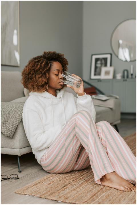 African American woman in hoodie sipping water, si