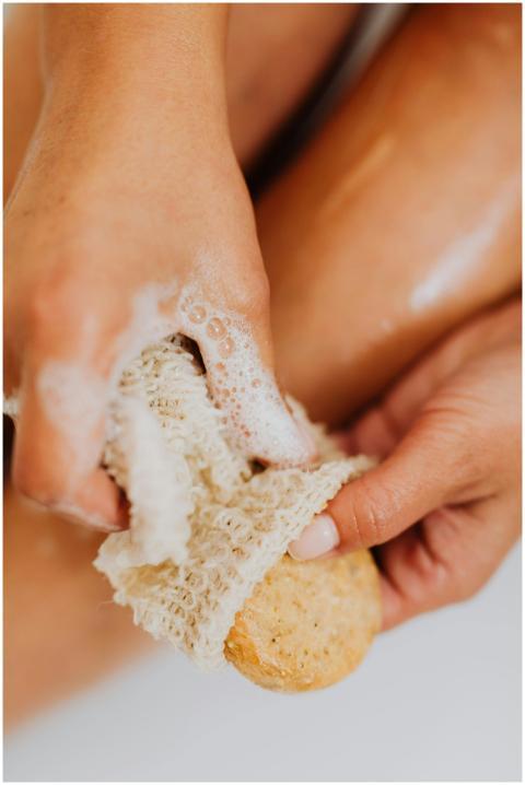 Close-up of a woman using a natural sponge and soa