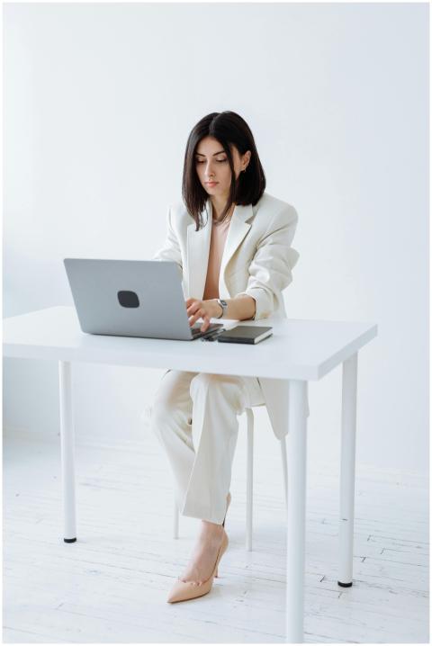 Businesswoman in a white suit working on a laptop
