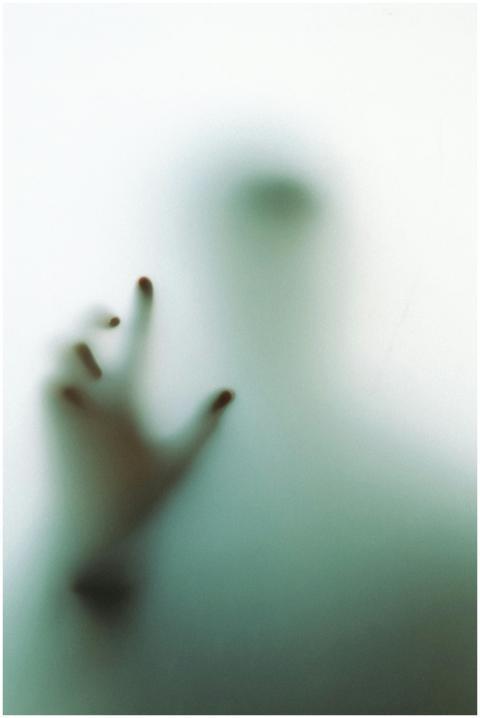 Blurred silhouette with hand on glass creating a m