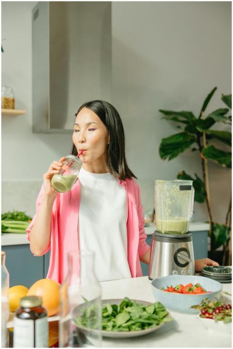 Asian woman sipping a green smoothie in a modern k