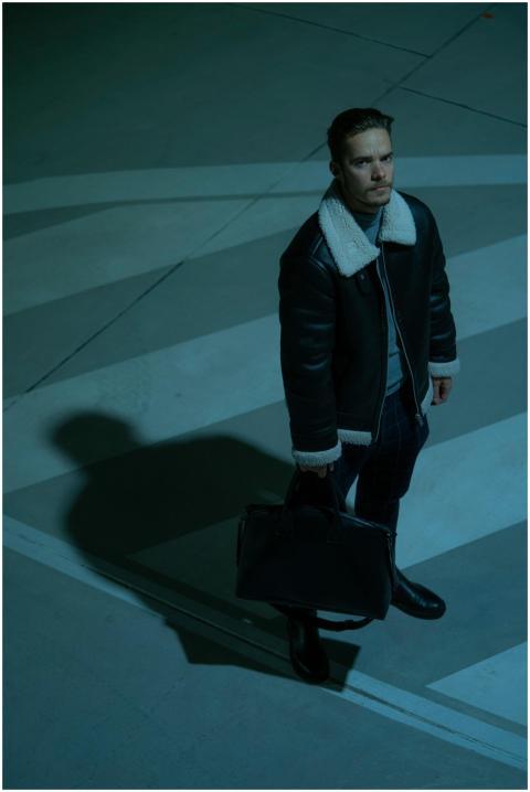 Stylish adult man in a leather jacket holding a ba