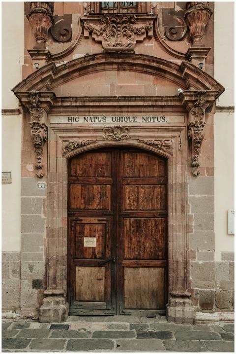 A vintage wooden door with ornate carvings and a L