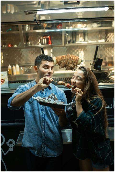 A couple savoring kebabs at a street food truck un