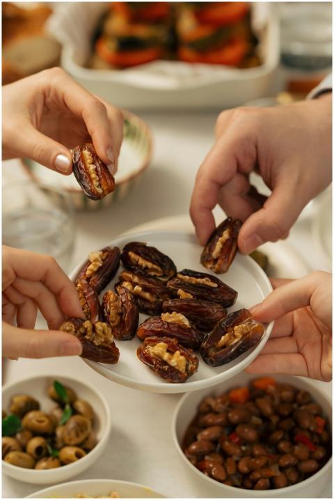 Hands reaching for stuffed dates at an iftar table