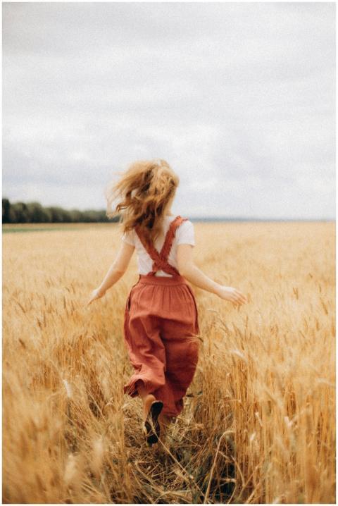 A carefree woman in a red skirt runs through a gol