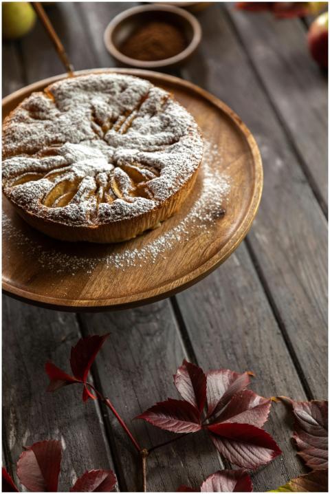 Rustic apple tart with powdered sugar on a wooden
