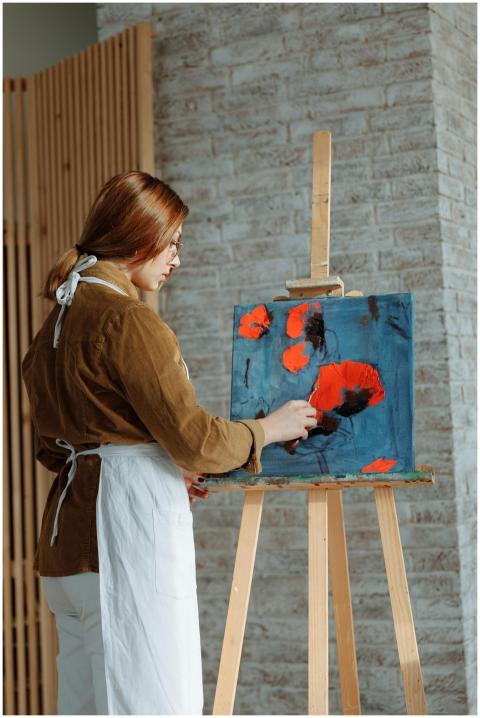 Artist painting a poppy flower painting on an ease