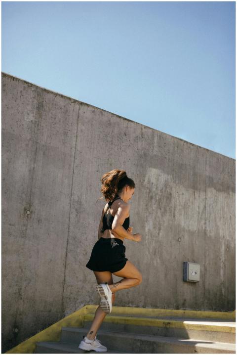 Athletic young woman in activewear running on outd