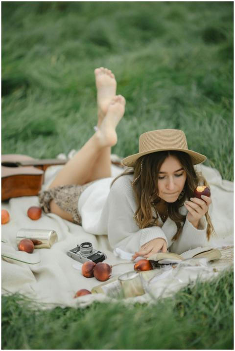 Woman enjoying a picnic on grass with peaches and