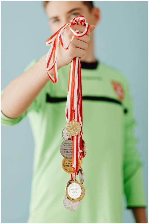 Teen wearing sports jersey displays multiple medal