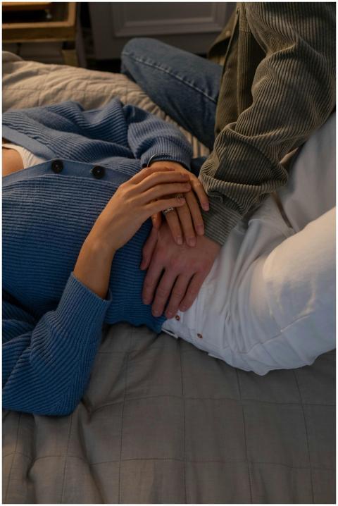 Couple relaxing on bed wearing cozy sweaters, capt