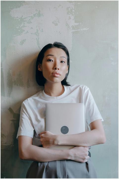 Asian woman in a white shirt holding a laptop, lea