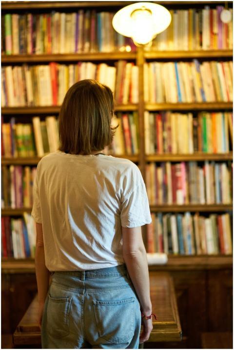 Woman in a library looking at bookshelves, creatin