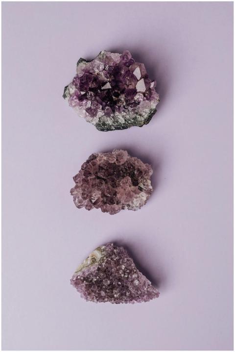 Three amethyst crystal clusters arranged on a past