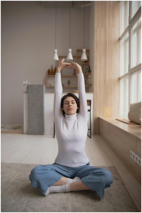 Woman seated in yoga pose stretching arms upwards