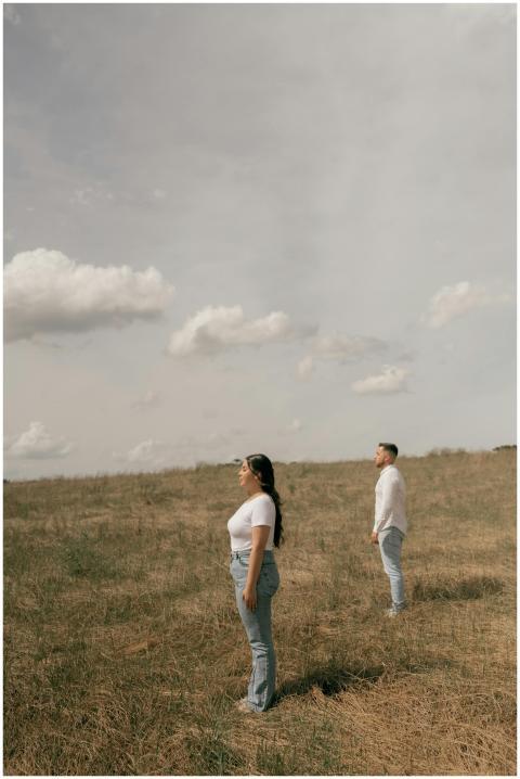 Two adults standing in an open field with a cloudy