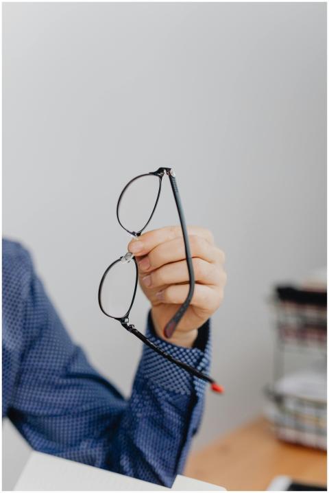 Close-up of a person holding eyeglasses indoors, p
